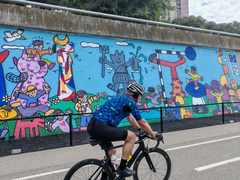 Un ciclista passa per davant del mural del Camil Escruela al BesArt